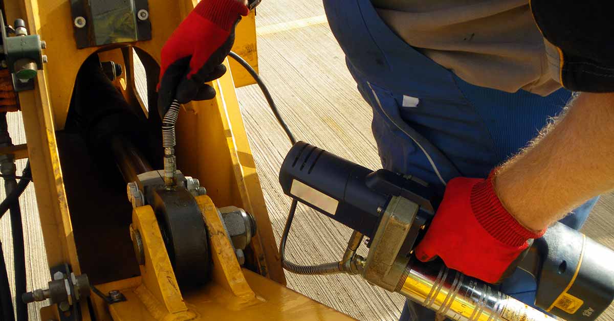 Crane operator performing crane lubrication procedures during pre-shift inspection - critical skills tested on NCCCO written and practical exams for LAT and TSS certification