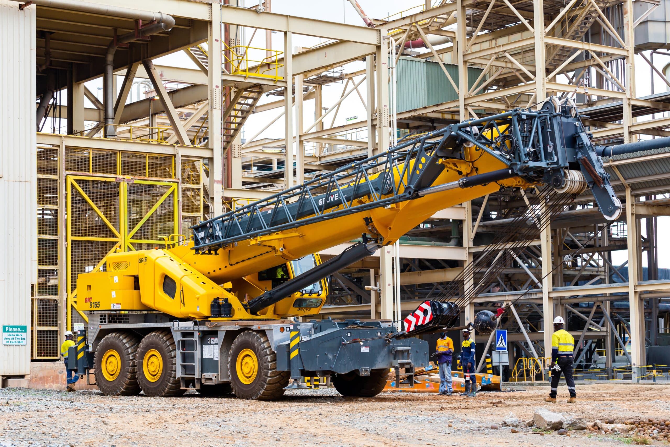Complete overview of Grove Crane Models Every Operator Should Know featuring certified crane operator executing lift plan with proper hand signals, ground crew coordination, and safety zone establishment per OSHA regulations