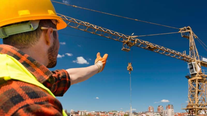 Complete overview of Crane Alert in Houston: What Every Operator Must Know featuring certified crane operator executing lift plan with proper hand signals, ground crew coordination, and safety zone establishment per OSHA regulations