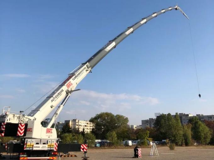 Complete overview of Understanding Crane Boom Deflection featuring certified crane operator executing lift plan with proper hand signals, ground crew coordination, and safety zone establishment per OSHA regulations