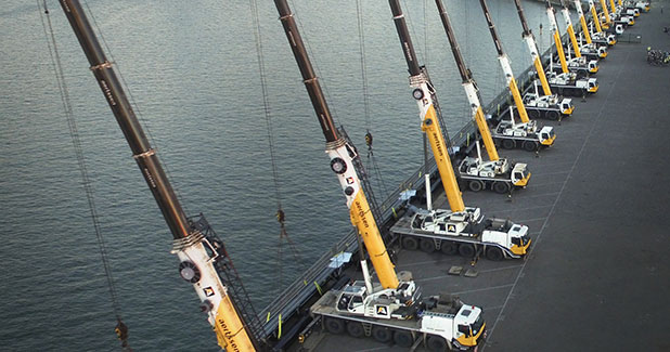 Complete overview of Multi-Crane Lift Procedures featuring certified crane operator executing lift plan with proper hand signals, ground crew coordination, and safety zone establishment per OSHA regulations
