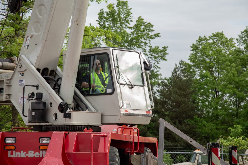 Complete overview of NCCCO Exam in Spanish and Other Languages featuring certified crane operator executing lift plan with proper hand signals, ground crew coordination, and safety zone establishment per OSHA regulations