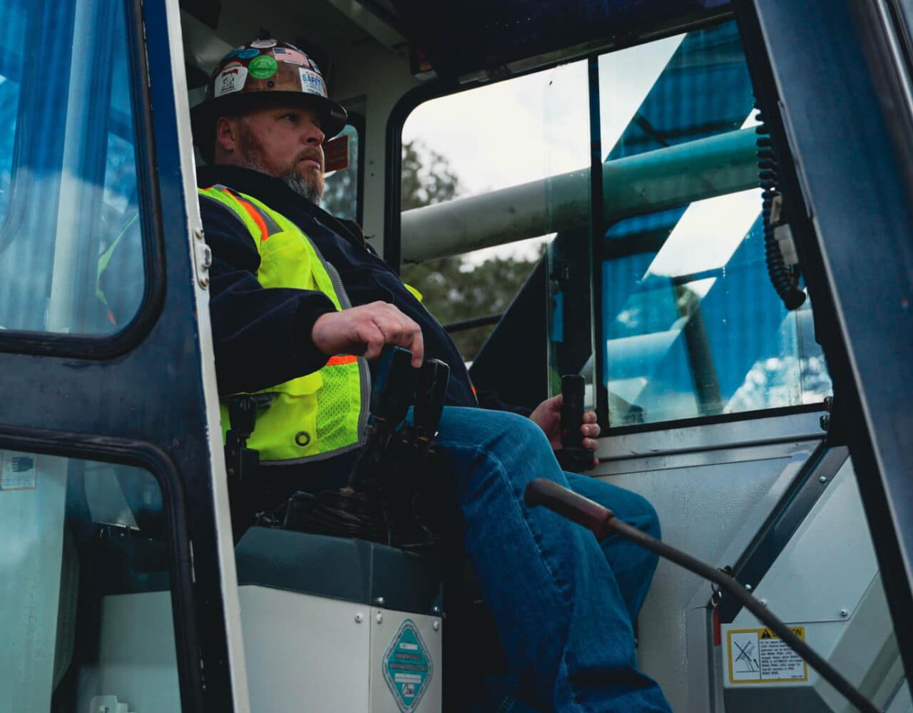 Complete overview of OSHA Crane Citation Types and Penalty Amounts featuring certified crane operator executing lift plan with proper hand signals, ground crew coordination, and safety zone establishment per OSHA regulations